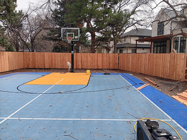 A basketball court surrounded by a fence installed by Loyal Landscaping.